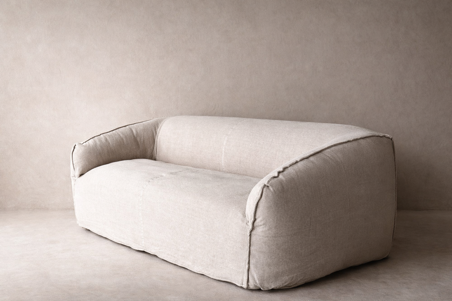 Cousin Sofa in pumice linen upholstery, featuring a low continuous form, rounded arms and deep seating.