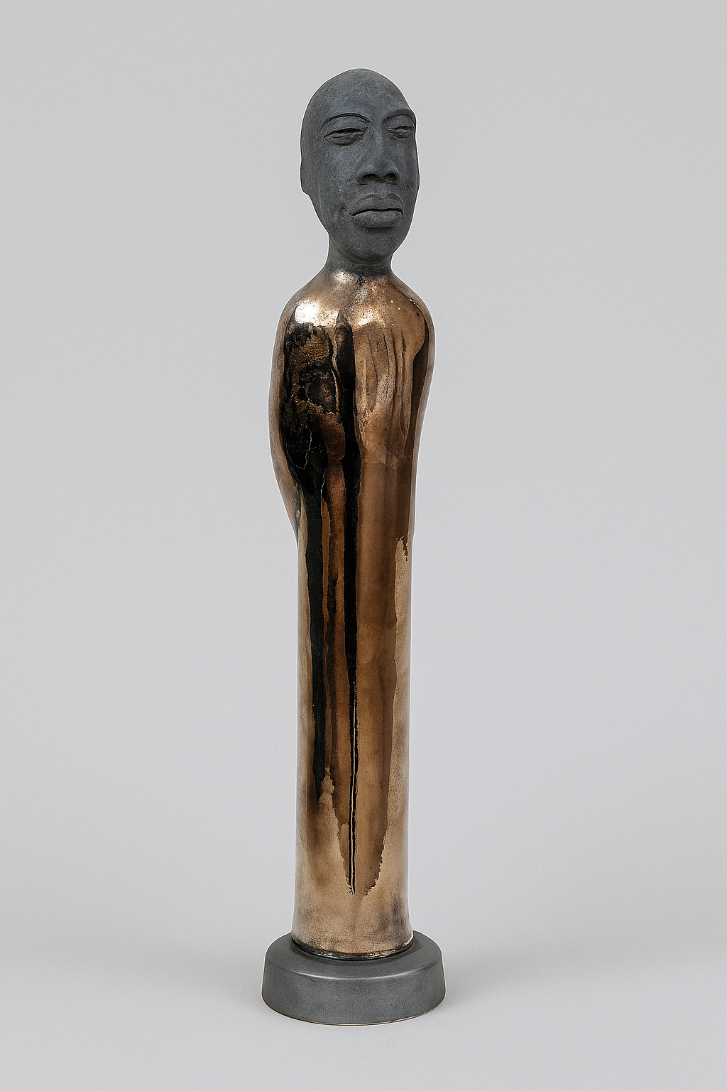 Bronze sculpture of a standing figure on a gray background