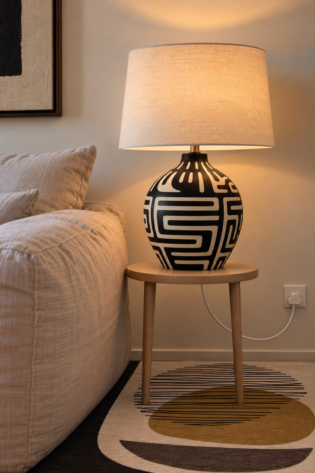 Terra lamp with a black ceramic base featuring a continuous monochrome graphic pattern inspired by Ugandan studio pottery, topped with a drum shade.