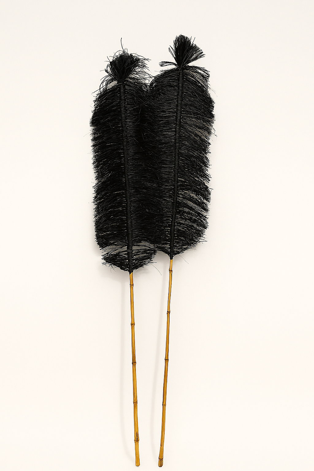 A pair of black handcrafted raffia and bamboo sticks with twisted rope-like texture, styled as decorative objects