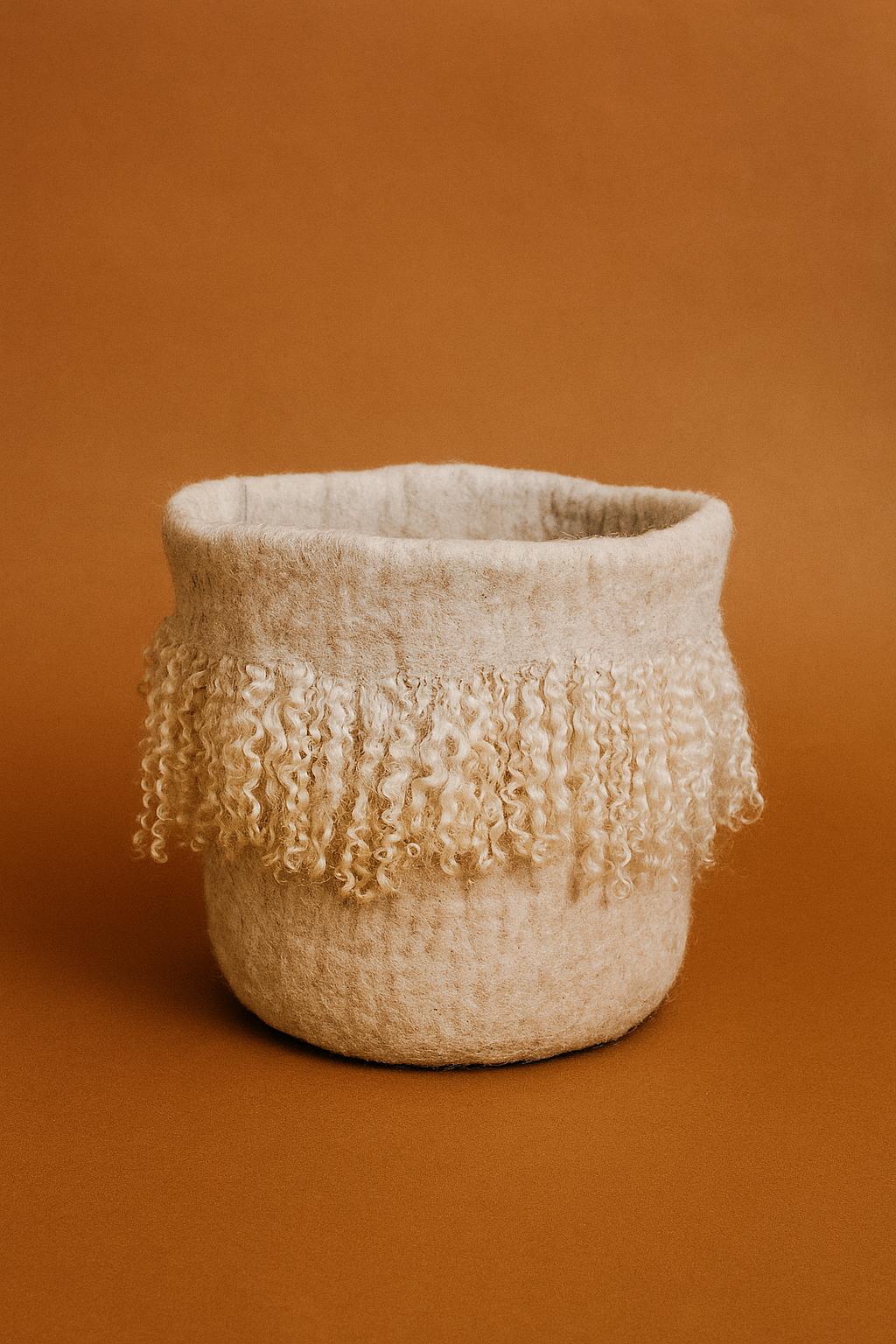 Textured felt basket with fringe on a brown background