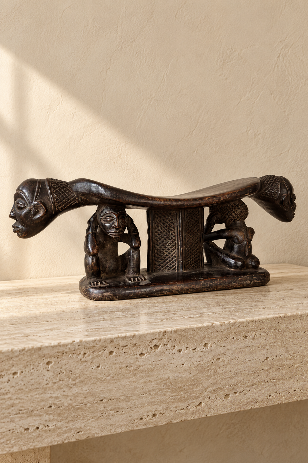 Luba headrest carved from dark wood, with a curved upper rest supported by human figures.⠋

