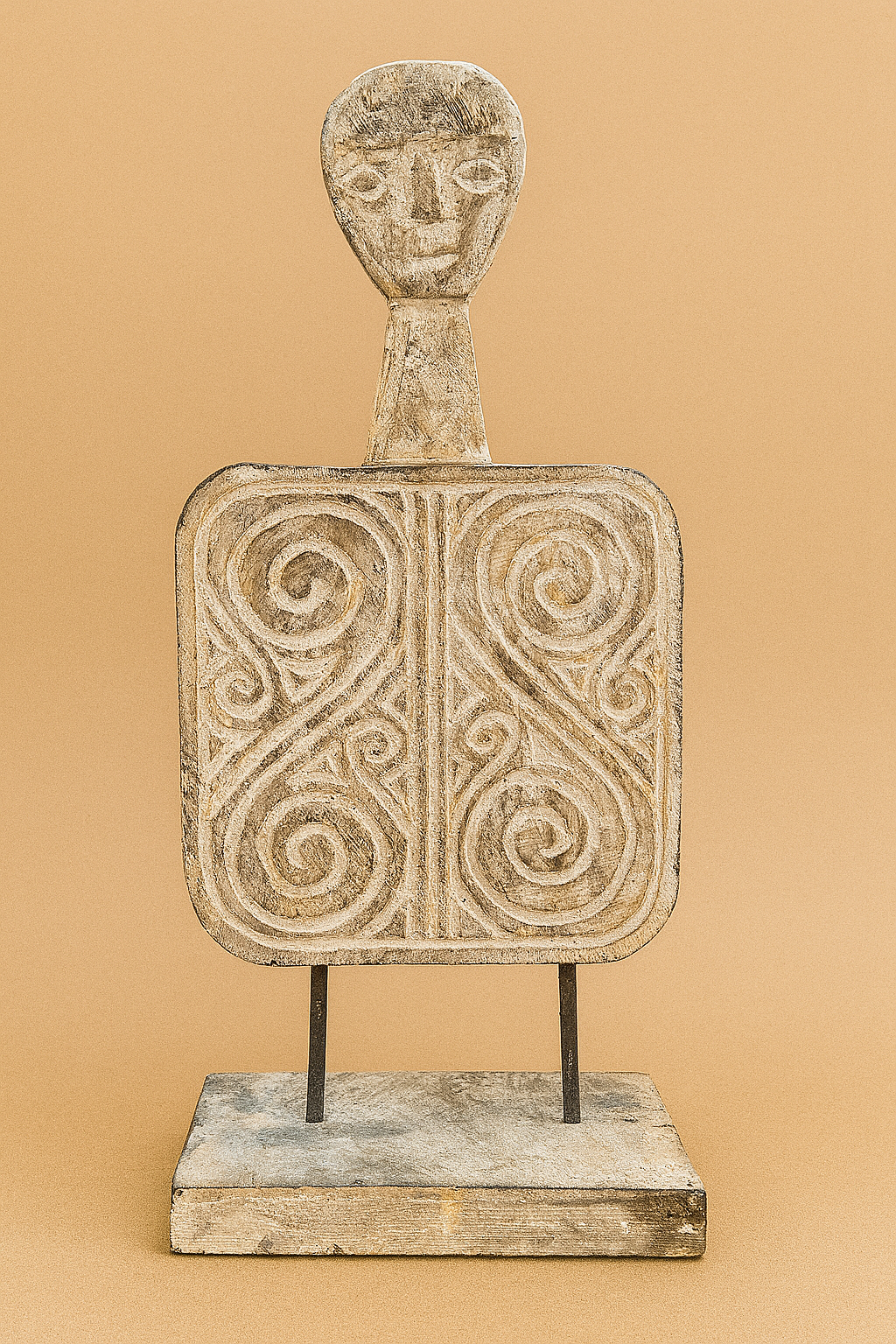 Hand-carved wooden sculpture with abstract face and tribal swirls, mounted on a rustic wood and metal base against a light brown background