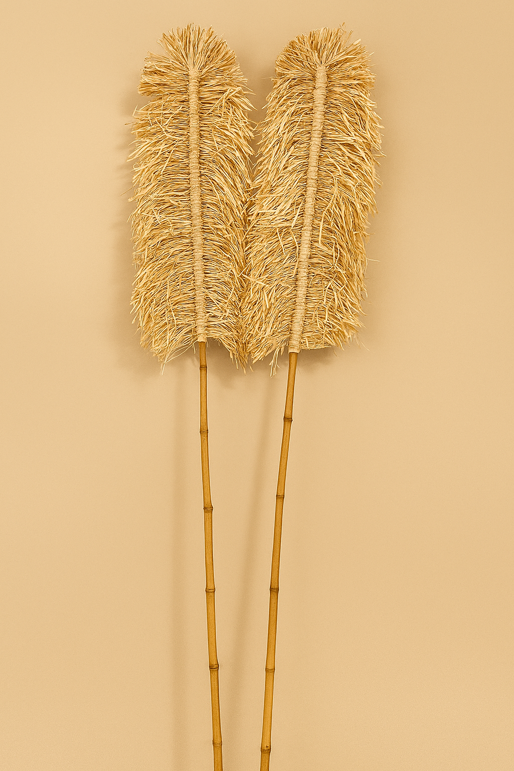 A pair of handcrafted raffia and bamboo sticks with twisted rope-like texture, styled as decorative objects